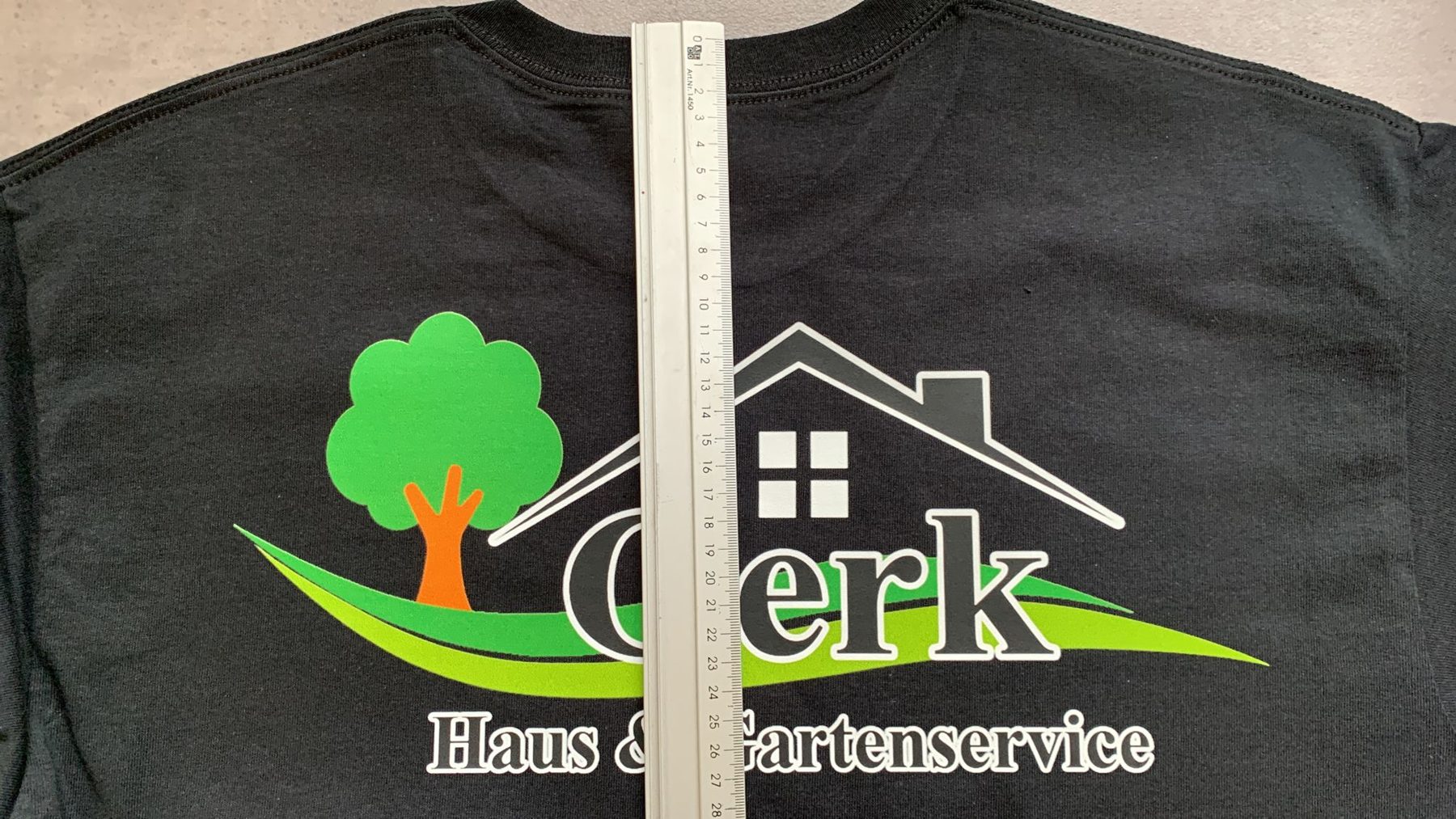 Schwarzes Shirt mit mehrfarbigem Logo eines Haus- und Gartenservices