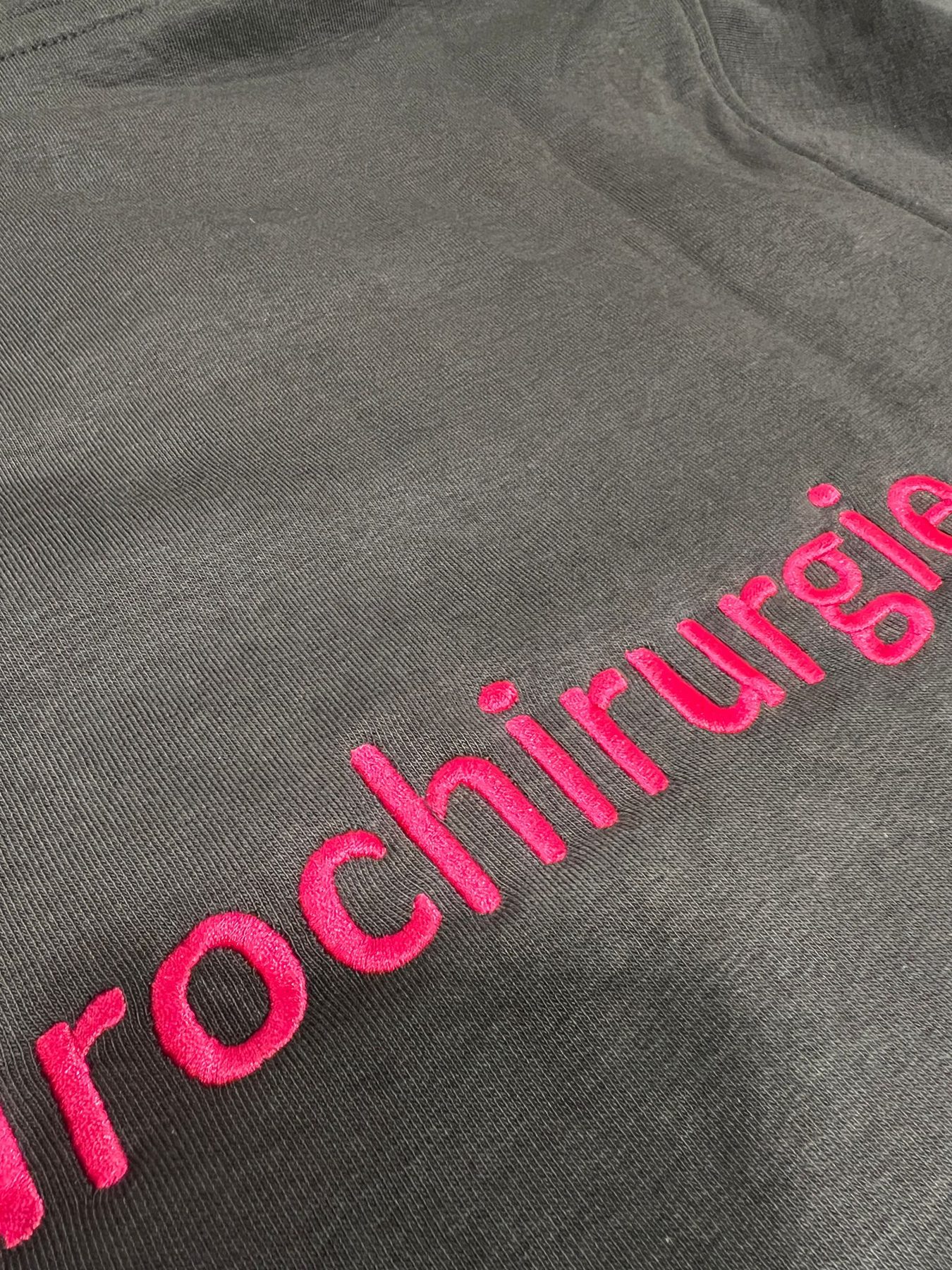 Pinker gestickter Schriftzug auf schwarzem Shirt, Nahaufnahme