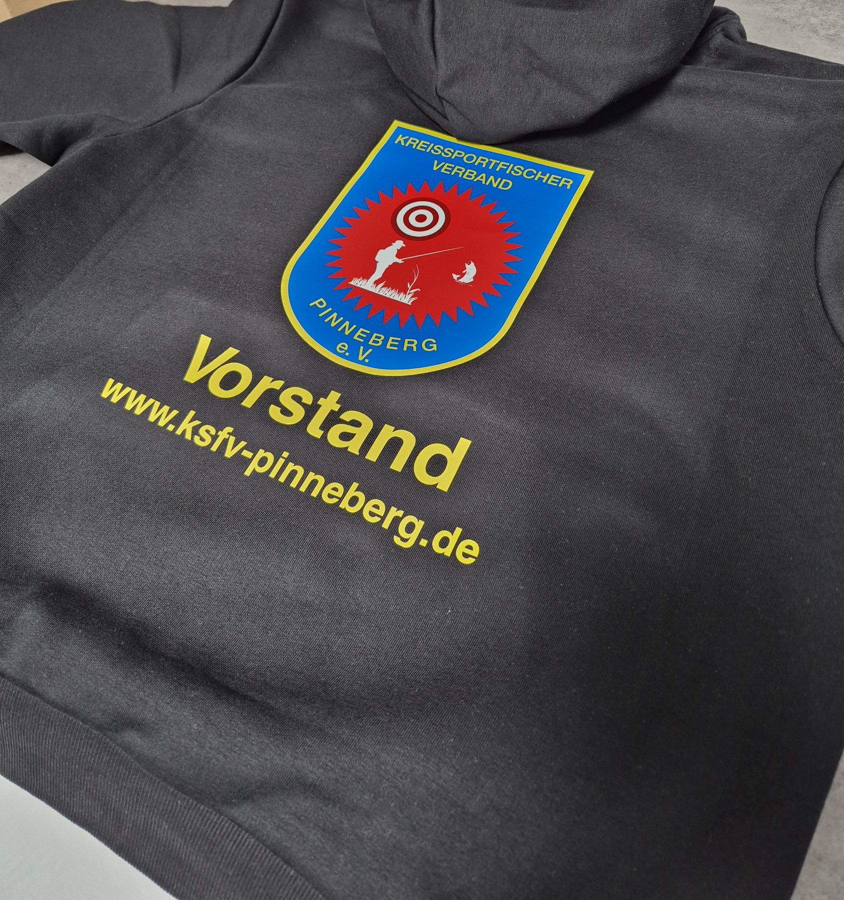 Schwarzer Hoodie mit farbigem Verbandswappen und dem Aufdruck Vorstand auf dem Rücken